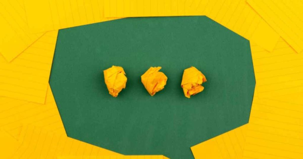 A green speech bubble with an ellipsis made of crumpled yellow note cards.